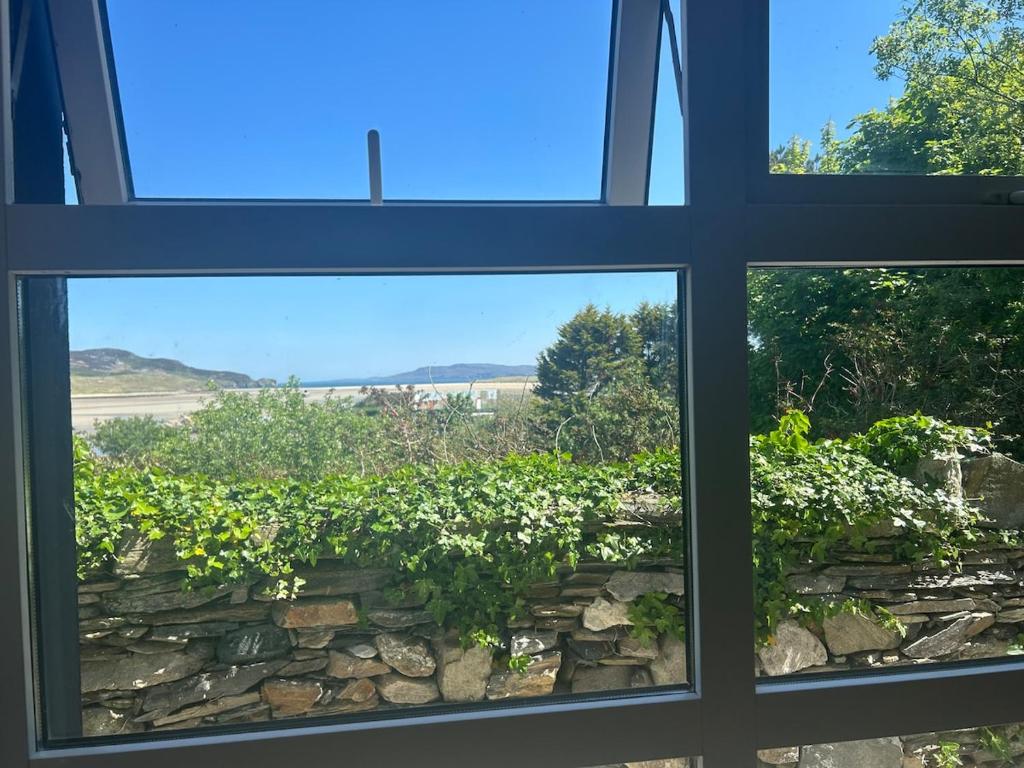 an open window looking out at a stone wall at Central Two Bed Apartment looking over the Harbour in Dunfanaghy