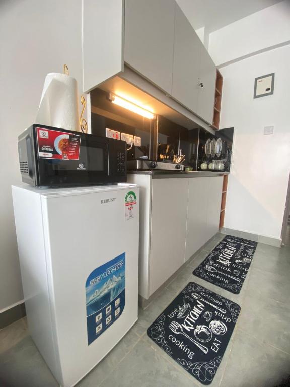 a kitchen with a microwave on top of a refrigerator at CozMila homes in Kiambu