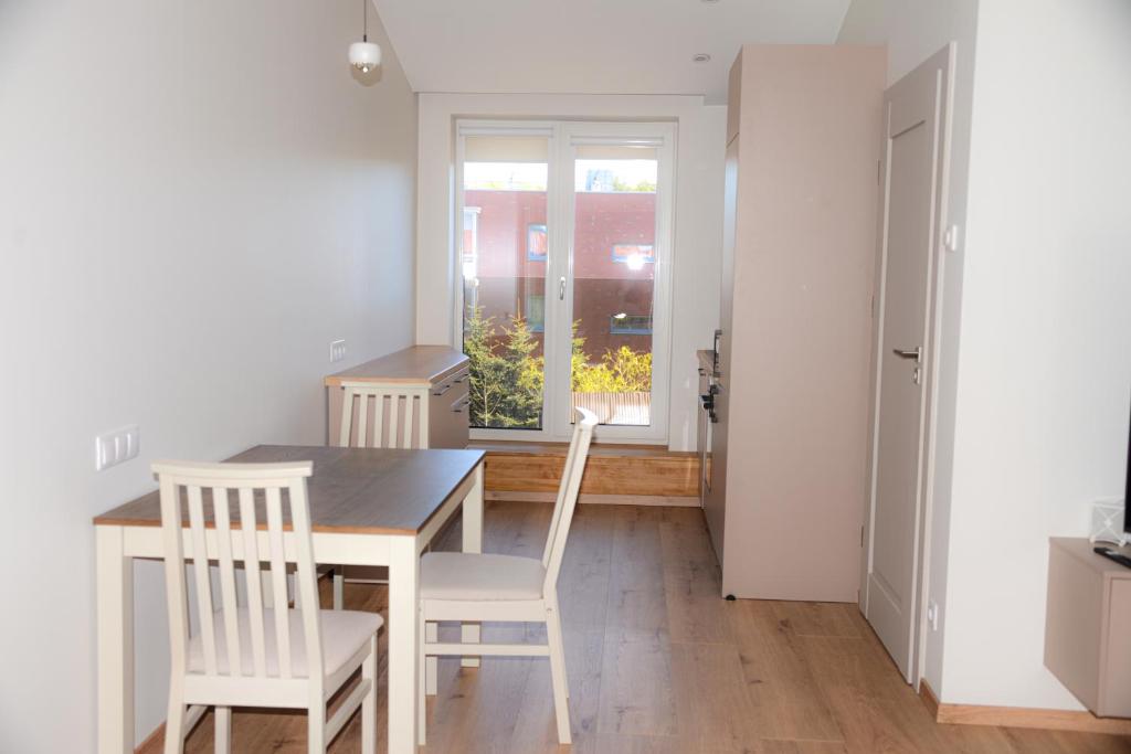 a kitchen with a table and chairs and a window at Erdvūs apartamentai Prie Jūros in Melnragė