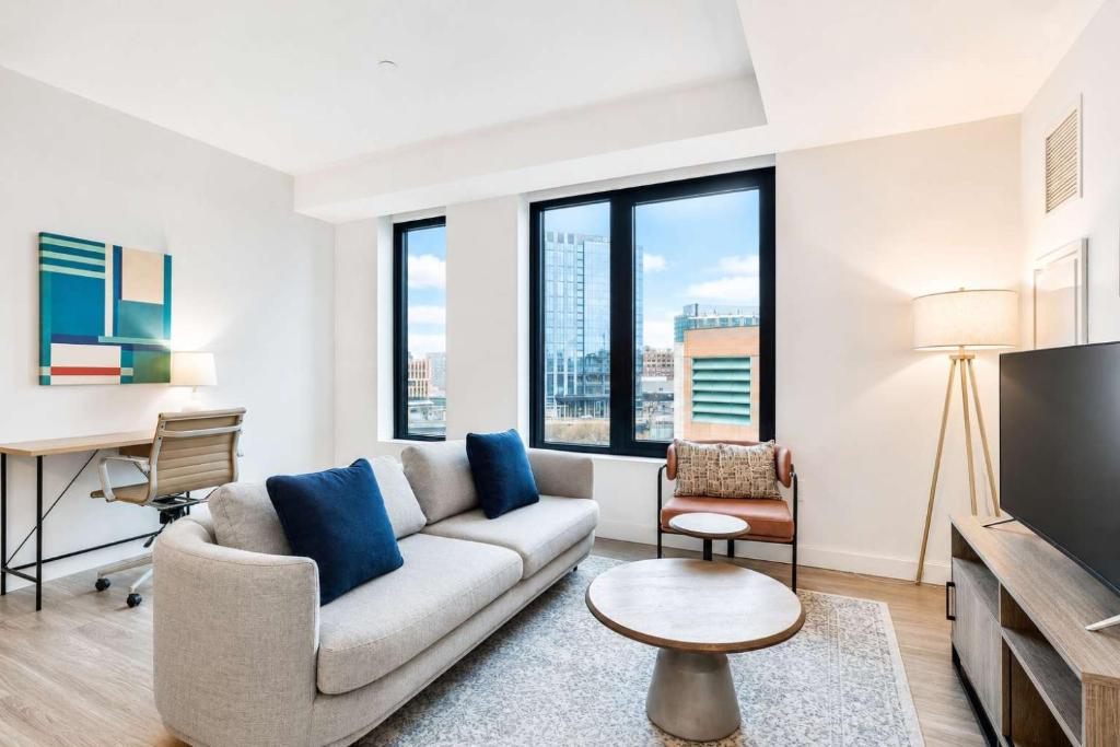 a living room with a couch and a tv at Luxury Seaport Stay Rooftop & Pool in Boston