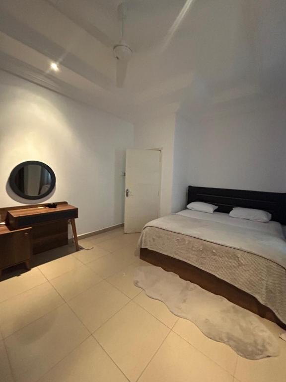 a bedroom with a bed and a table and a mirror at Fawis Lodge in Brusubi