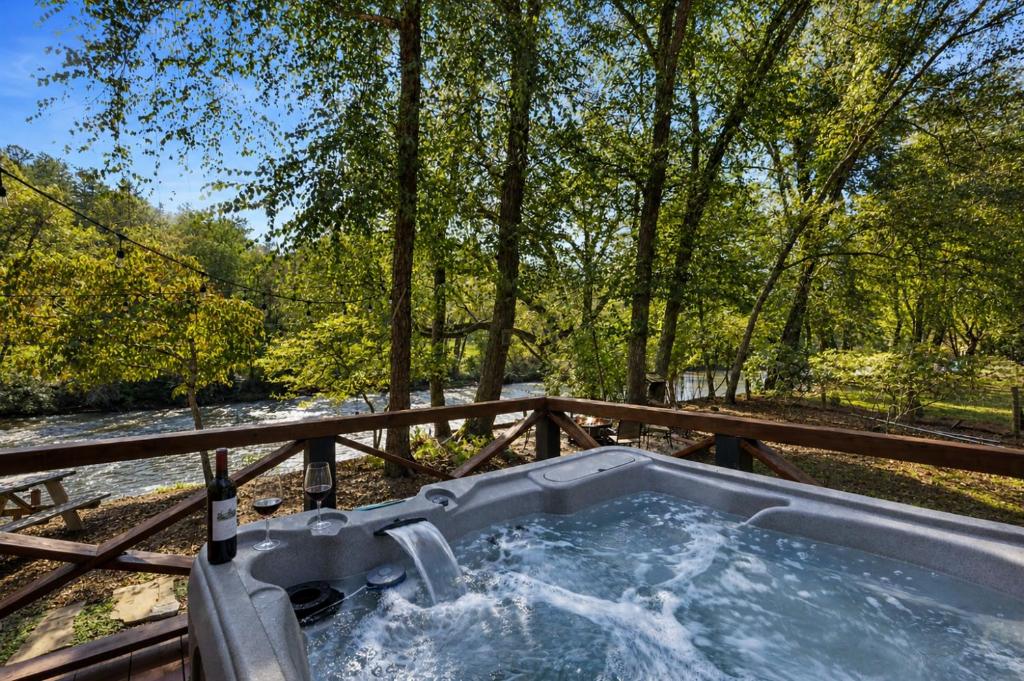 a jacuzzi tub in the woods next to a river at A Rivers Edge in Mineral Bluff