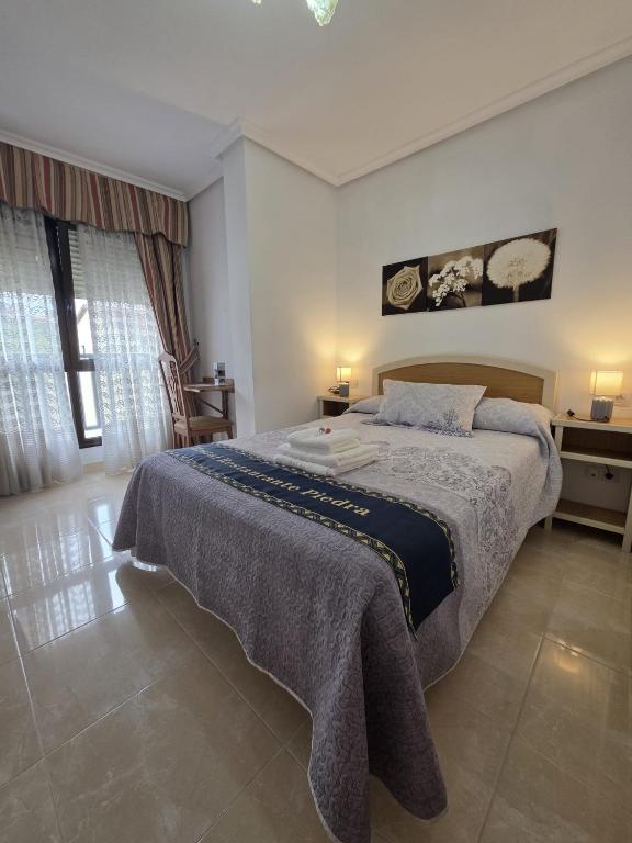 a bedroom with a large bed and two windows at Hostal Restaurante Piedra in Limpias