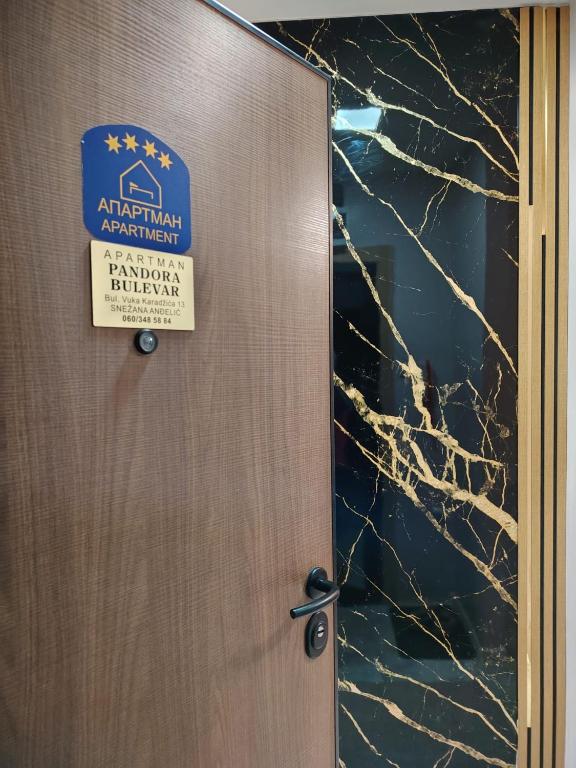 a sign on a door with a sign for an apartmentagent at PANDORA BULEVAR Cacak in Čačak
