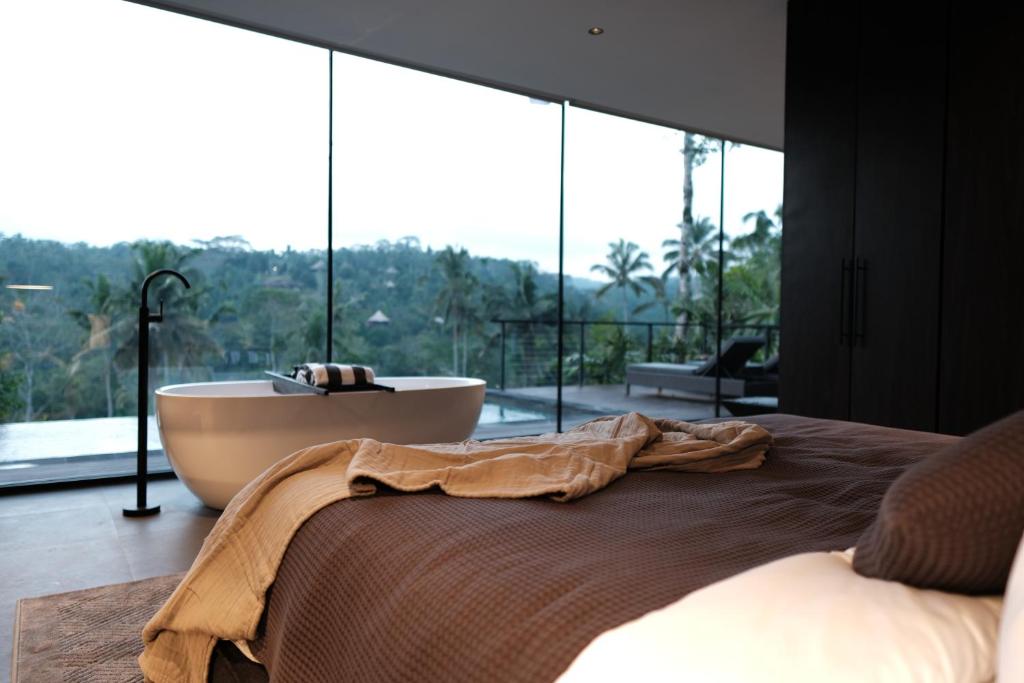a bedroom with a bath tub and a large window at The Ruler Bali in Penginyahan