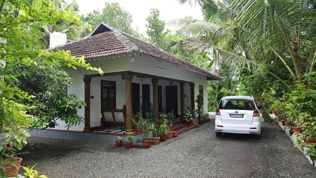 a white car parked in front of a small house at Writer's Inn in Vaikom