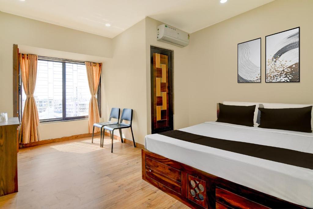 a bedroom with a bed and a chair and a window at Hotel O B&B Guest House in kolkata