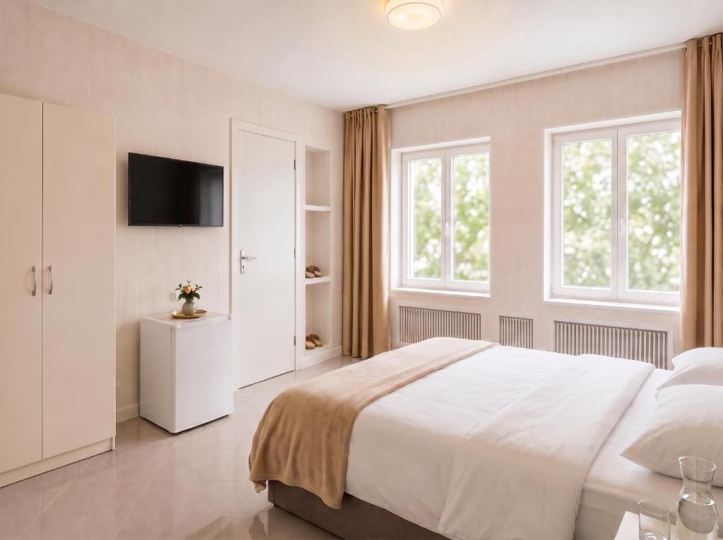 a white bedroom with a large bed and windows at Pension Elisa in Rheinfelden