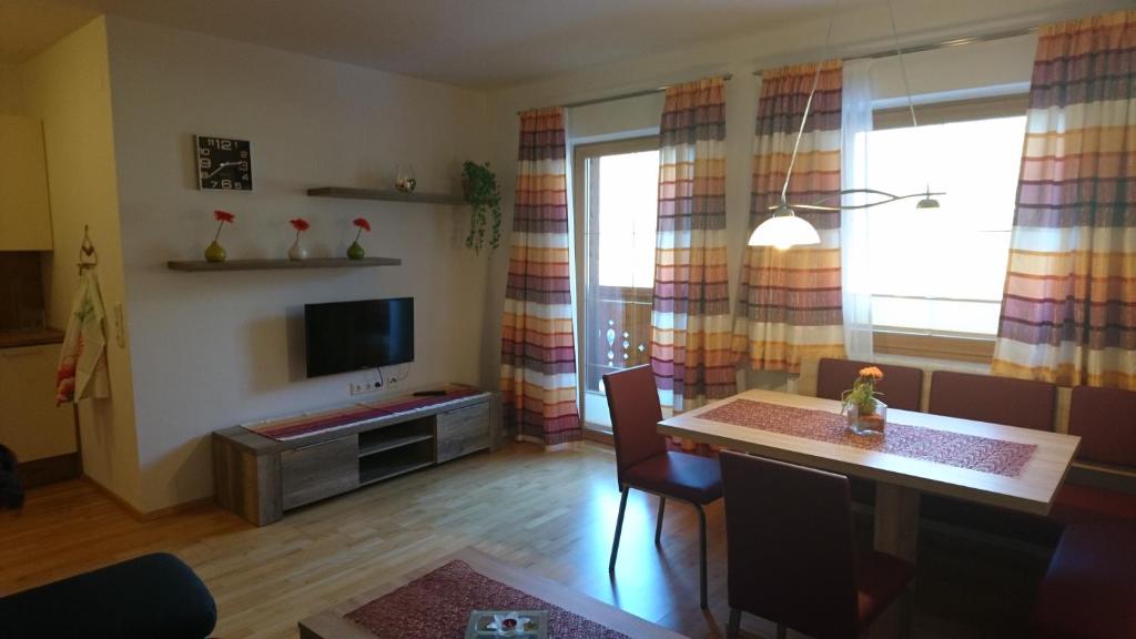 een woonkamer met een tafel en een televisie bij Weitblick Appartements in Bad Hofgastein