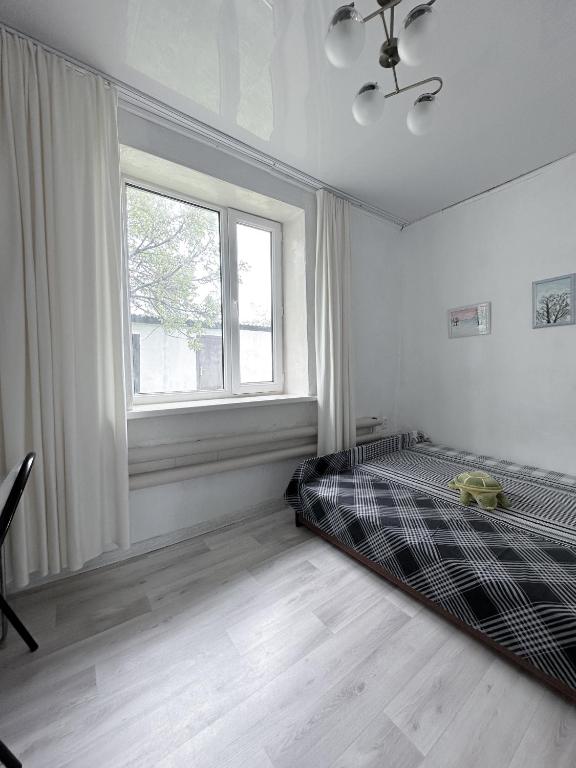 a white bedroom with a bed and a window at Mountain View Guest House in Zhabagly