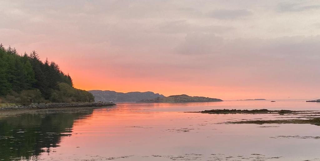 a sunset over the water with mountains in the background at Bunessan Inn in Bunessan