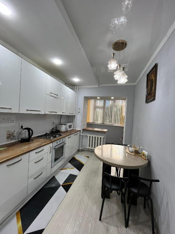 a kitchen with white cabinets and a table in it at Downtown Homestay in Bishkek