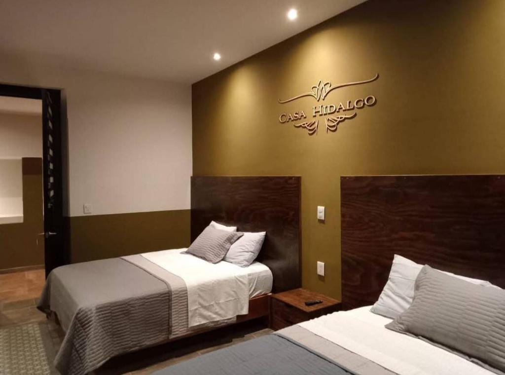 a bedroom with two beds and a sign on the wall at Casa Hidalgo in Ciudad Hidalgo