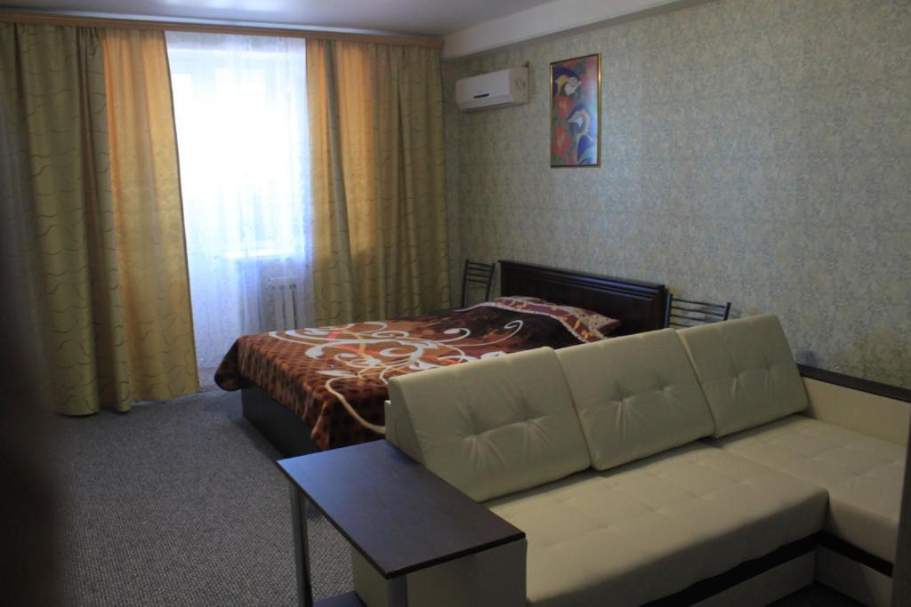 een slaapkamer met een bed, een bank en een raam bij Квартиры Калинина 161А in Nevinnomyssk