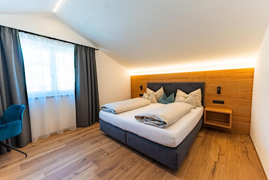 a bedroom with a bed and a large window at AurAlpin Apartments in Cadipietra