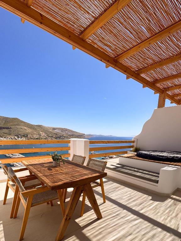 a wooden table and chairs on a patio with the ocean at Spongia Apartments and Suites Kalymnos in Kalymnos
