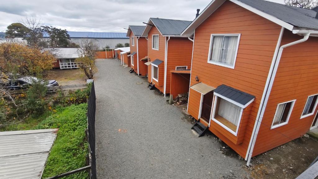 a row of orange houses parked next to a fence at Cabañas Ohiggins in Dalcahue