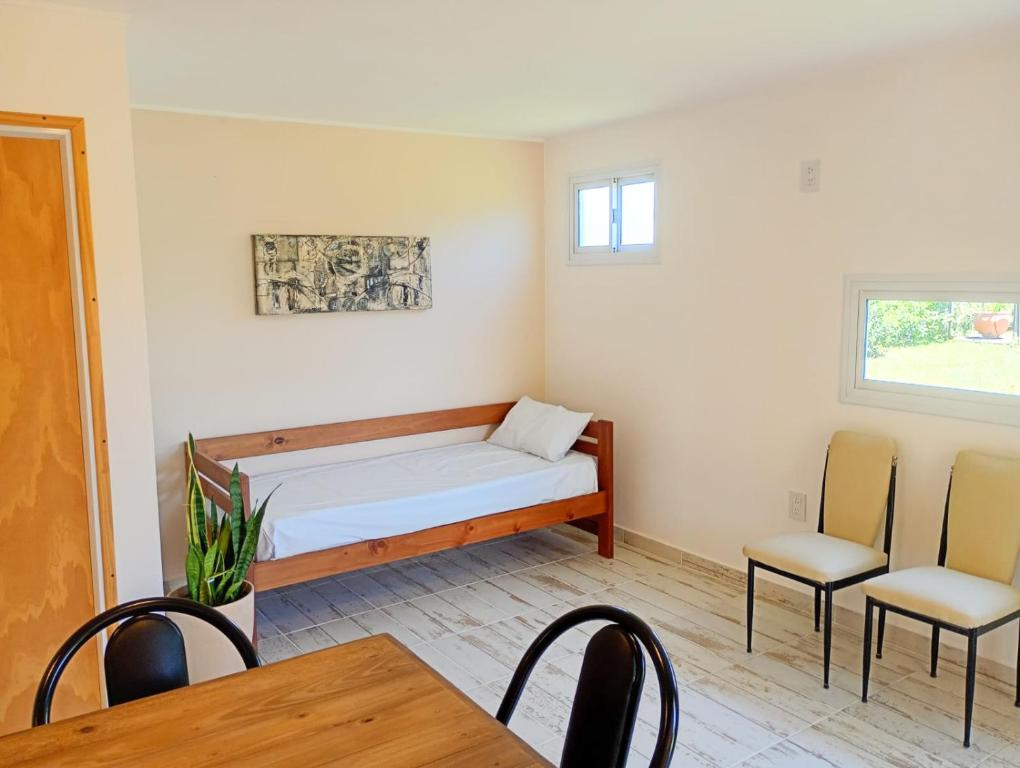 a room with a bed and two chairs and a table at Complejo ruka del pinar in San Ignacio
