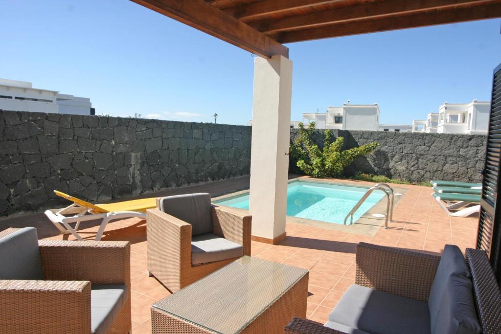 a patio with chairs and a swimming pool at VILLA BERMEJA 10 by Villitas in Playa Blanca