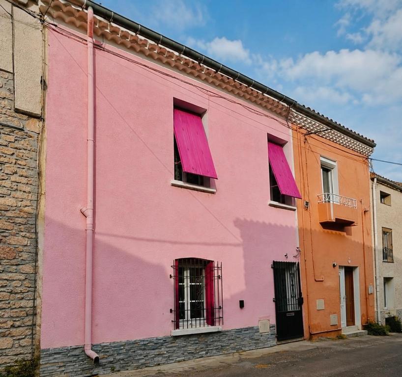 a pink building with red shutters on a street at Studio Cosy et Moderne in Saint-Ambroix