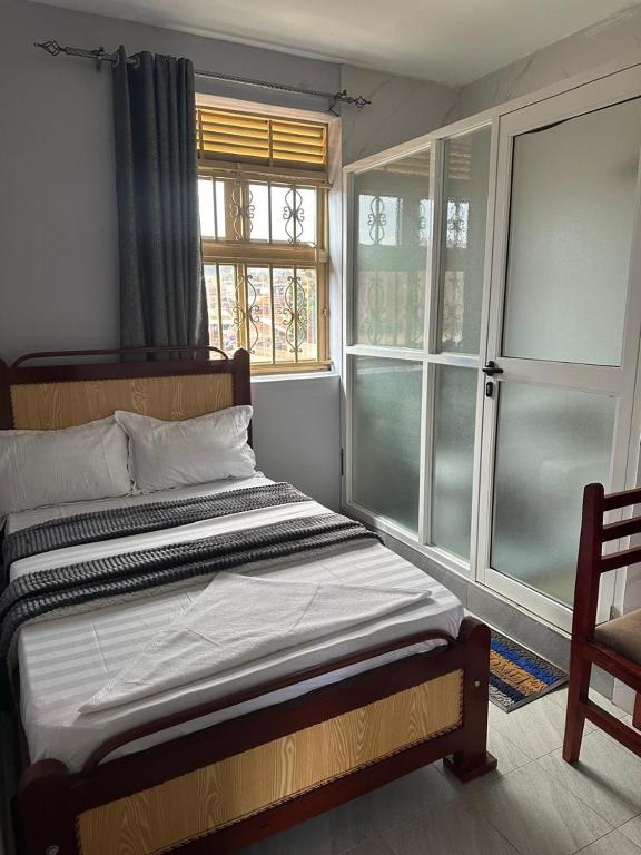 a bed in a room with two windows at Zone hotel and guest house in Bugembe