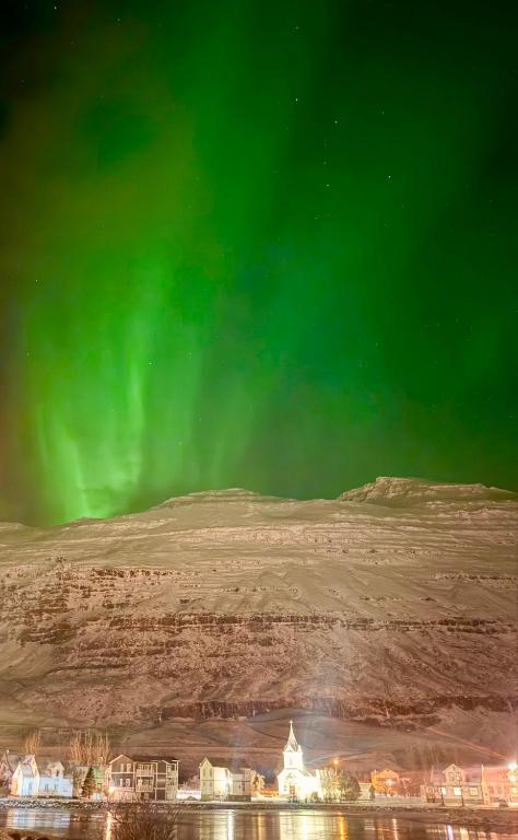 an image of the aurora borealis in the sky at Nýlenda - Charming Two Bedroom Seaside Property, Mountain and Town Views in Seyðisfjörður
