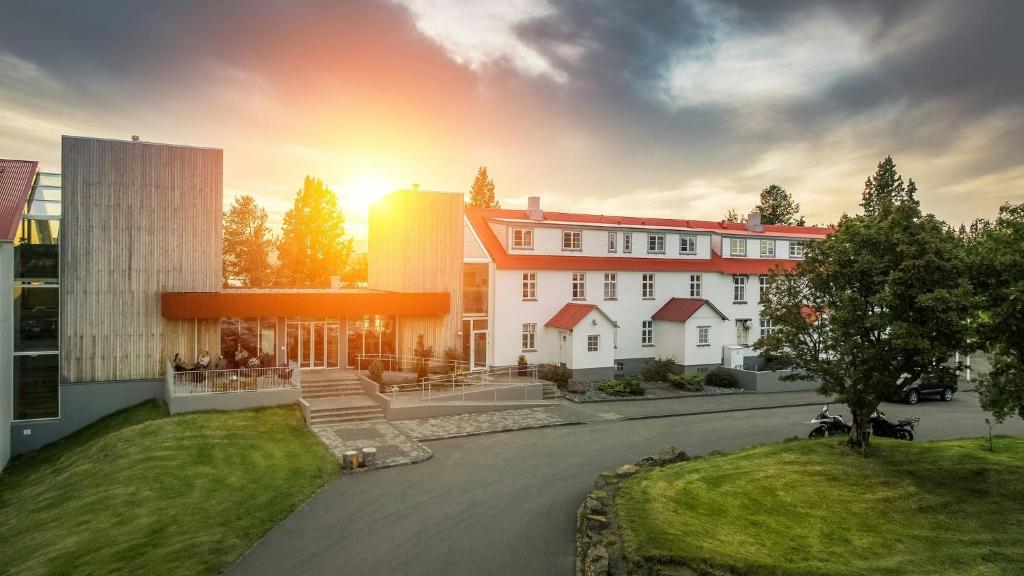 a large white building with a sunset in the background at Gistihúsið - Lake Hotel Egilsstadir in Egilsstaðir