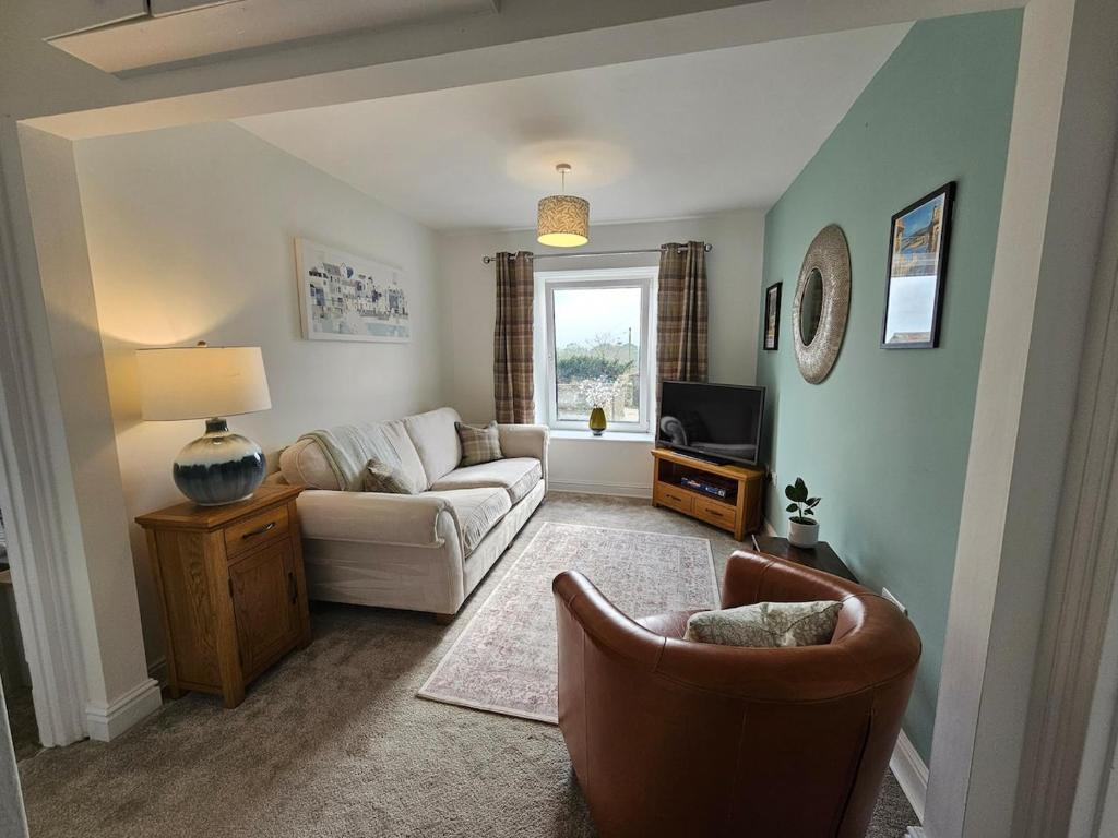 a living room with a couch and a tv at Railway Cottage, Liskeard in Liskeard