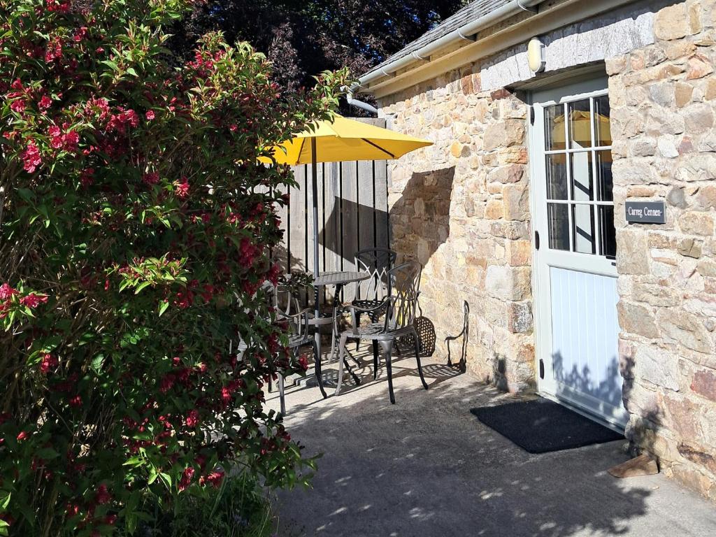 a patio with a table and an umbrella next to a building at Carreg Cennen Cottage in Carmarthen