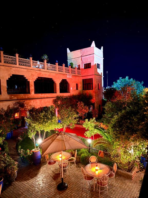 a building with tables and chairs and an umbrella at Riad Tama & SPA - Authentic Ourzazate Stay in Ouarzazate