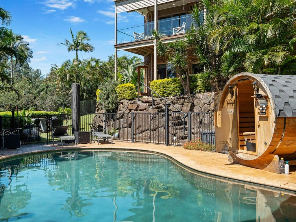 a swimming pool in front of a house at King bed studio seperate entry sauna pool garden view in Terranora