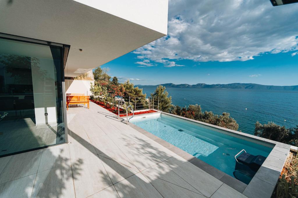 a house with a swimming pool and a view of the water at Villa Deluxe Zaostrog in Zaostrog