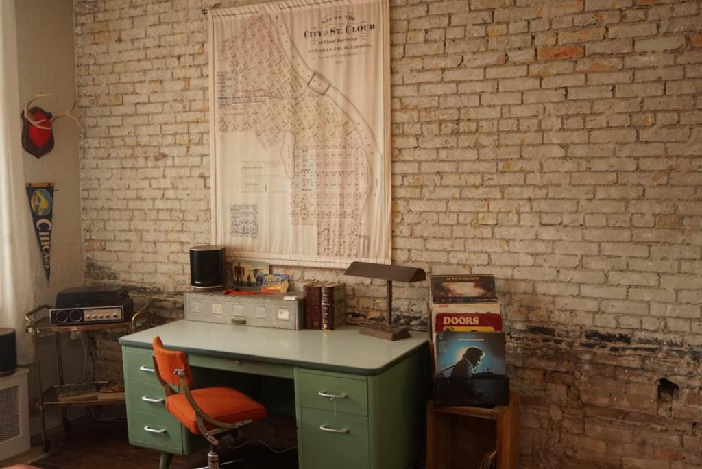 an office with a green desk and a brick wall at The Grey Cannon Guest House in Saint Cloud