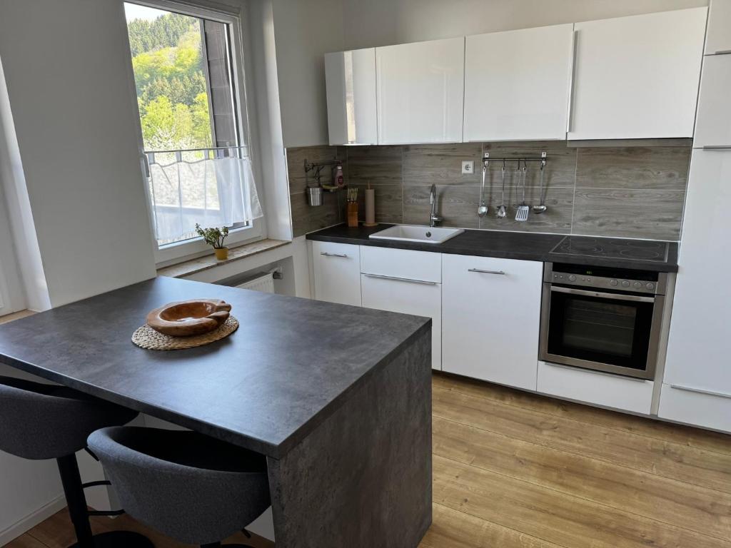 a kitchen with white cabinets and a table with a bowl on it at Chalet Relax in Birresborn