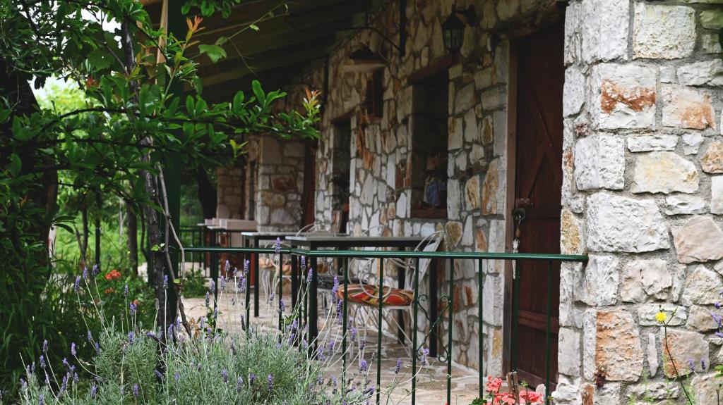 a porch of a stone building with a table and a chair at Filoxenia - The Place of Experience in Himare