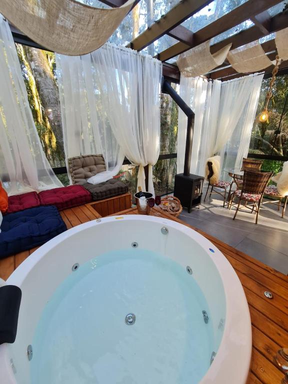 a bath tub in a room with windows at Chalés Serras House Casa Verde e Casa Laranja in São Francisco de Paula