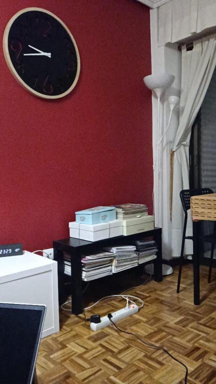 a living room with a clock on a red wall at Enjoy Valladolid in Valladolid
