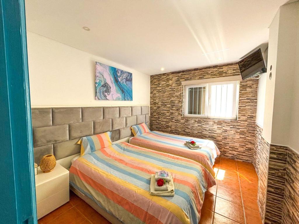 a bedroom with two beds and a brick wall at Casa da Pedra in Moledo