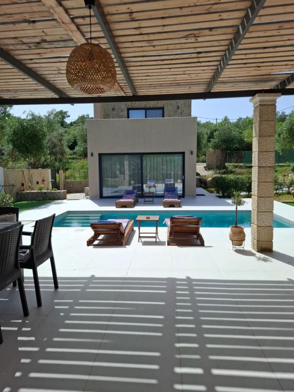 a patio with a pool and a table and chairs at Stones villa corfu in Varypatádes