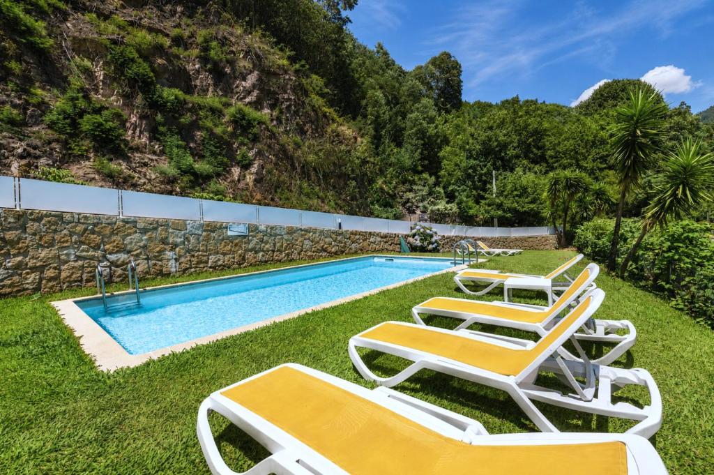 a group of lounge chairs and a swimming pool at Gerês Trail House in Geres