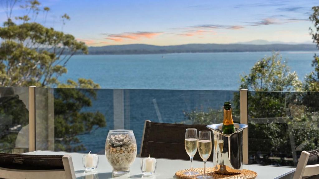 a table with two glasses and a bottle of wine at Mirage 1 24 Gloucester Street in Nelson Bay