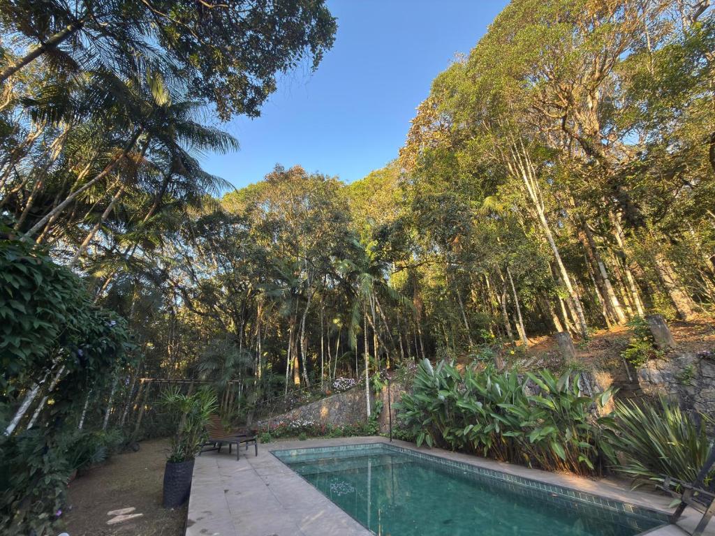 a swimming pool in a garden with trees in the background at Imperial Rodrigues Valley in Juquitiba