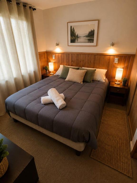 a bedroom with a large bed with two towels on it at Refugio del volcán in Pucón