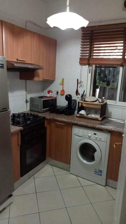 a kitchen with a washing machine and a stove at Coquet ac accès autonome in El Aouina Station