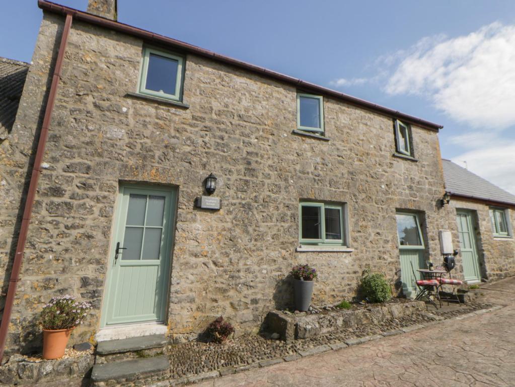 an old stone house with green doors and windows at Swallows Retreat in Kilgetty