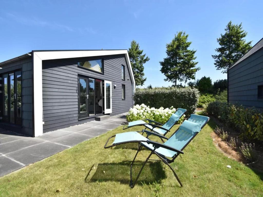 a couple of chairs sitting on the grass in front of a tiny house at Vogeltrek in Kattendijke