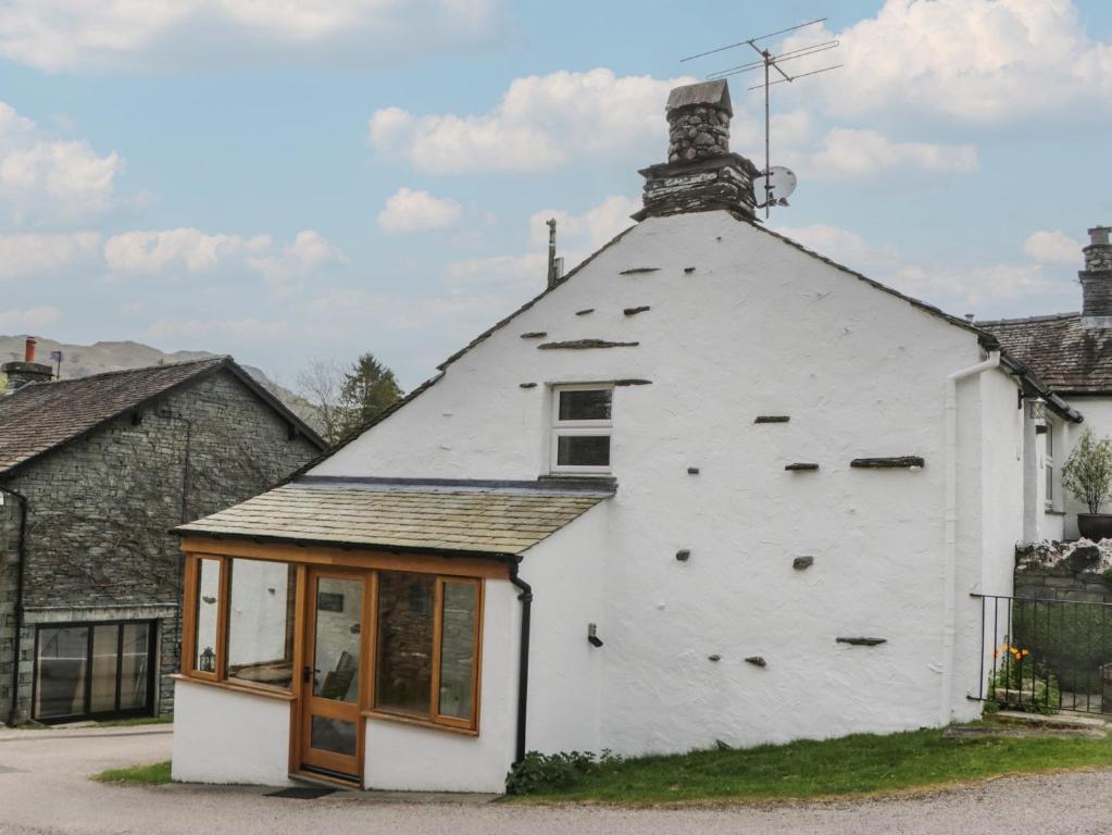 a white building with a chimney on top of it at Woodloft Cottage in Elterwater