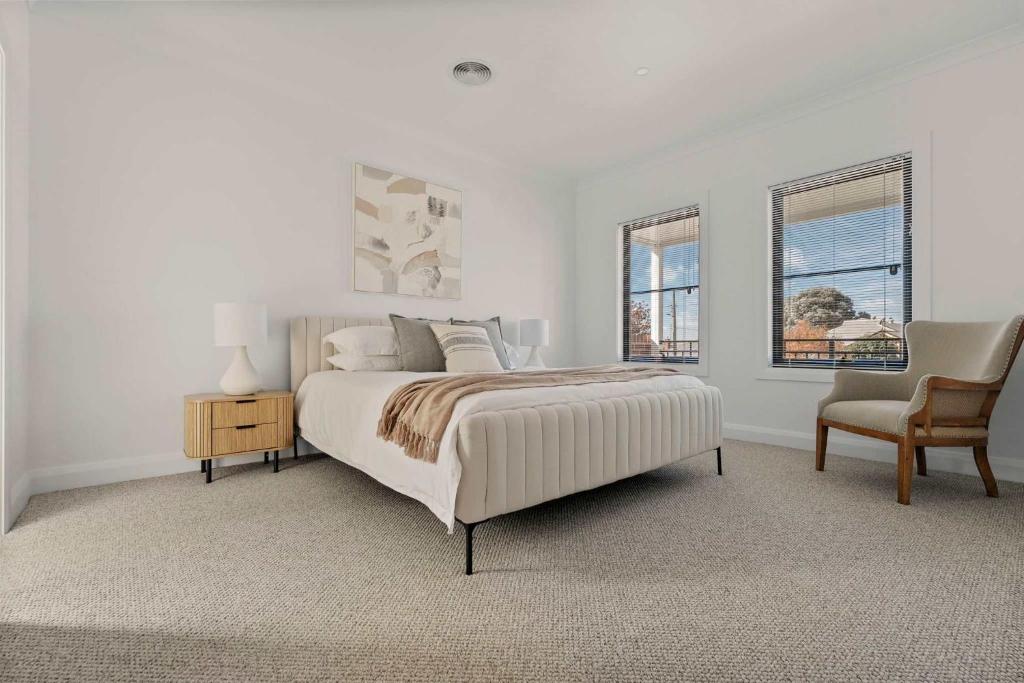 a white bedroom with a bed and a chair at Stylish & New 2 Bed & 2 Bath Apartment in Bathurst