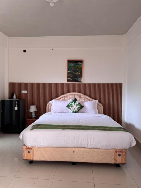 ein Schlafzimmer mit einem großen Bett mit hölzernem Kopfteil in der Unterkunft Leokase Hotel in Dili