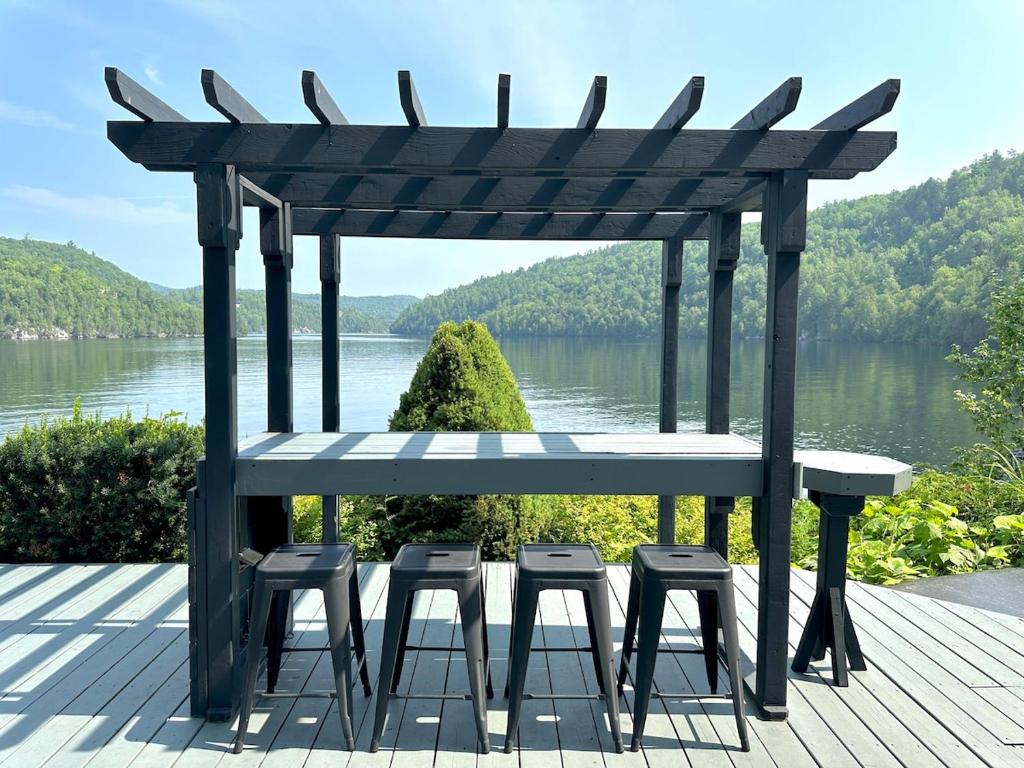 a pergola with four stools on a deck with a lake at Lakehouse Paradise in Val des Monts
